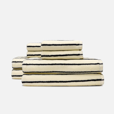 Cotton bath towels in cream with black stripes, stacked.