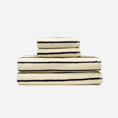Cotton bath towels, cream with black stripes, stacked.