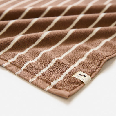 Bath towel, plush material with white stripes and corner fabric tag.