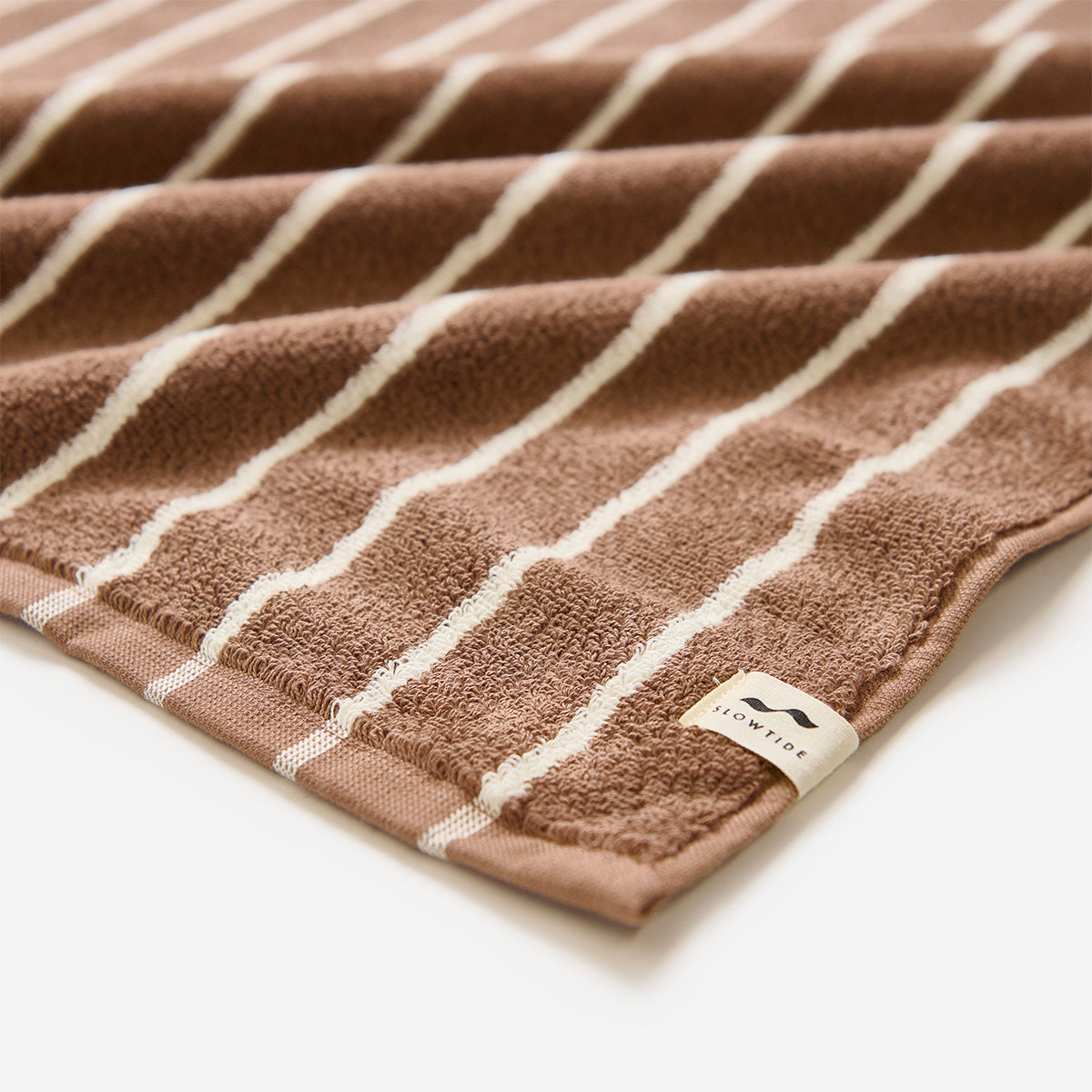 Bath towel, plush material with white stripes and corner fabric tag.