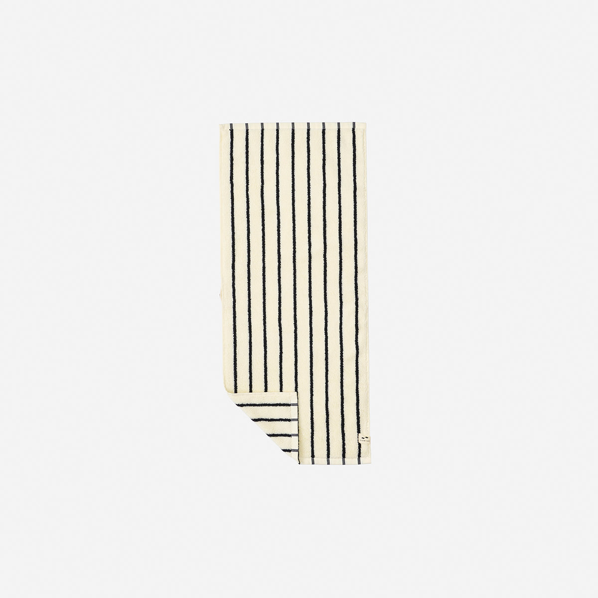 Cotton towel in cream with vertical black stripes, partially folded on white surface.