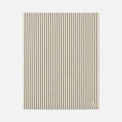 Beige rectangular rug with thin black stripes, suitable for layering with blankets.
