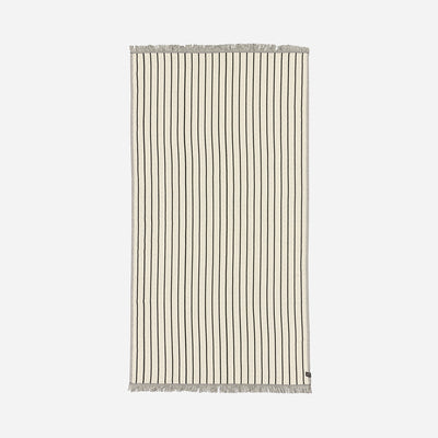 Turkish towel, lightweight beige cotton with thin black stripes and fringe on short ends.