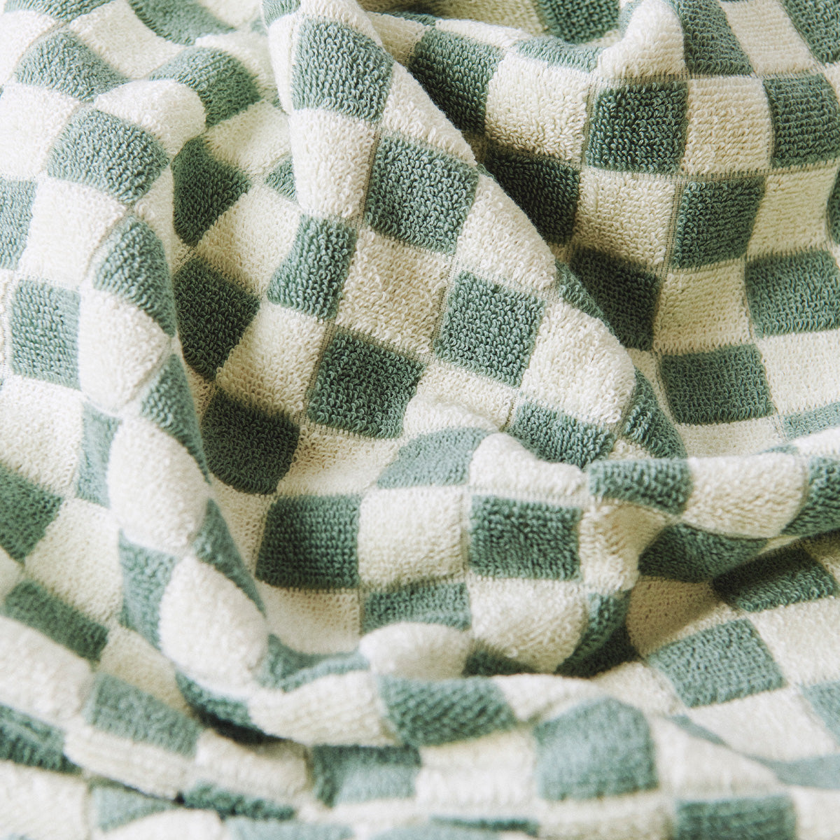 Woven fabric in sage and white checkerboard pattern with gentle folds.