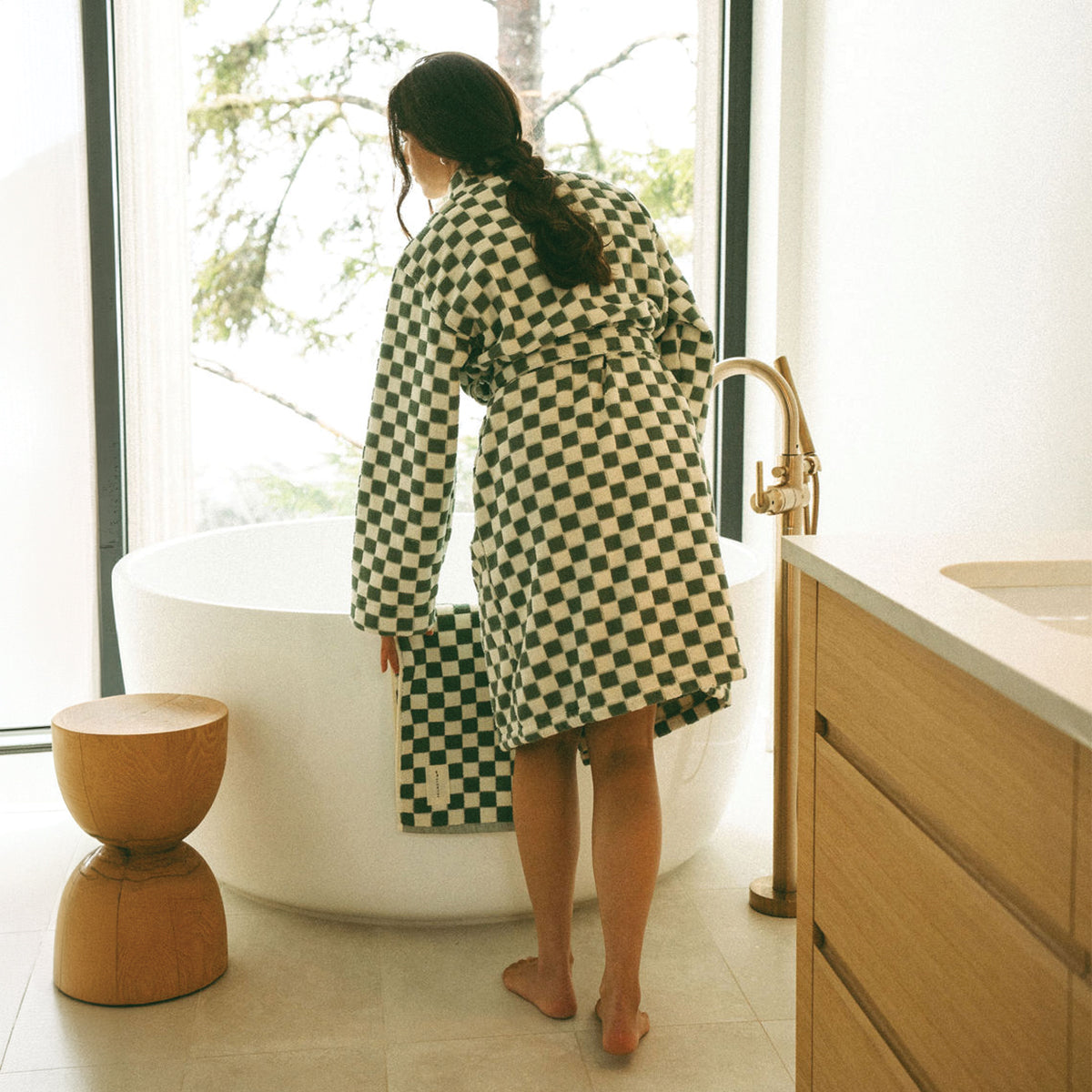Plush checkerboard bathrobe in green and white by a soaking tub.