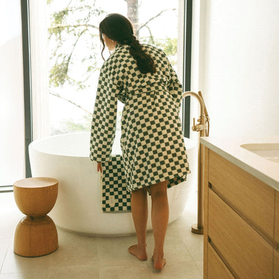 Plush checkerboard bathrobe in green and white by a soaking tub.
