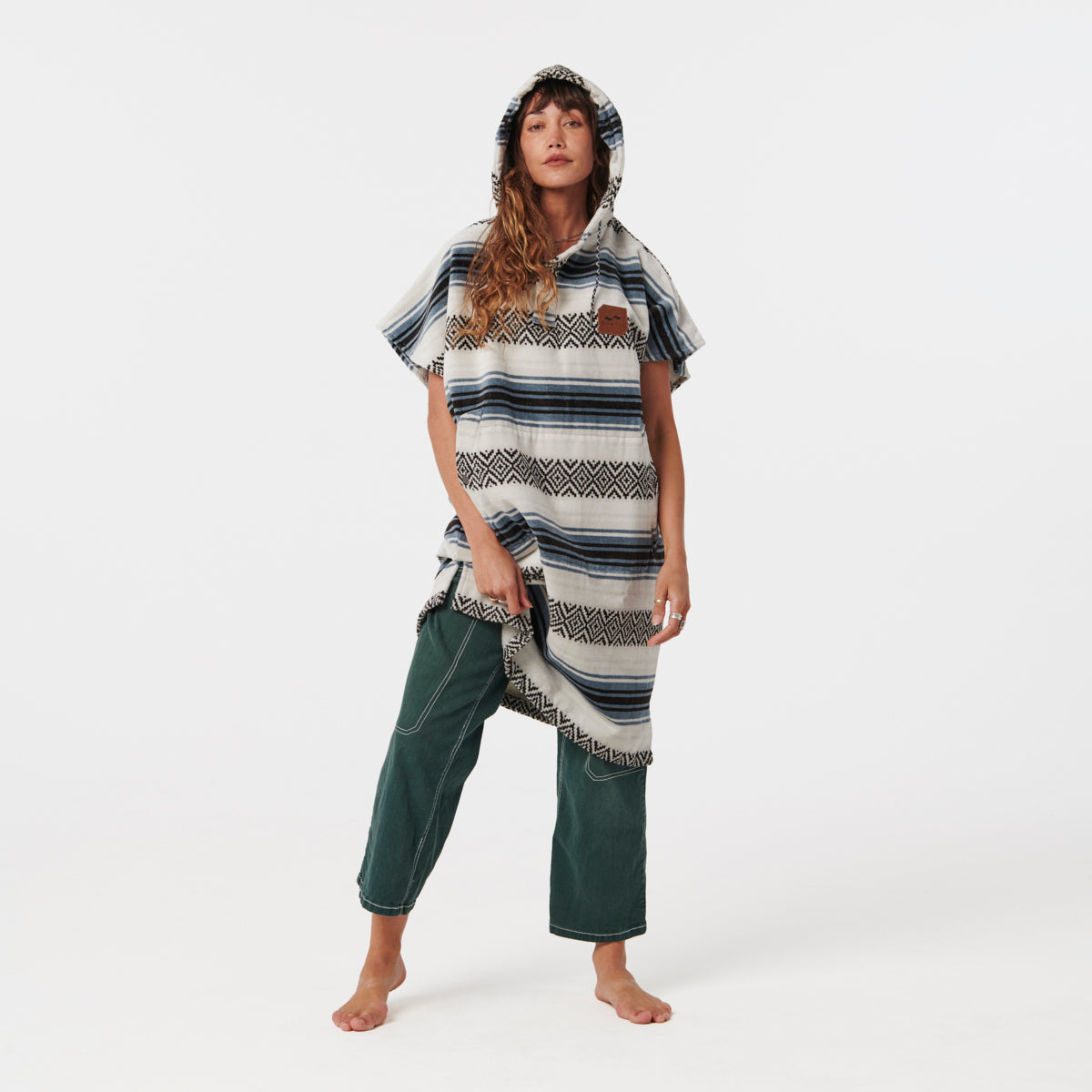 Hooded towel poncho in patterned absorbent cotton with green pants, for kids after bath or swim.