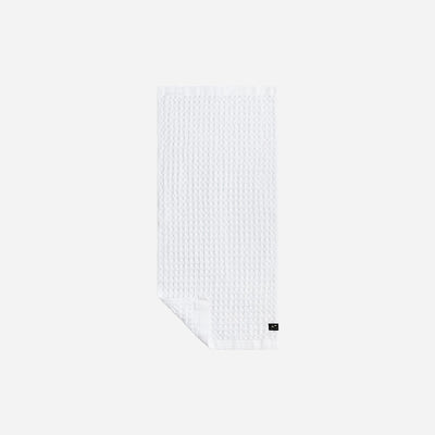 White waffle bath towel with black label detail on a plain light background.