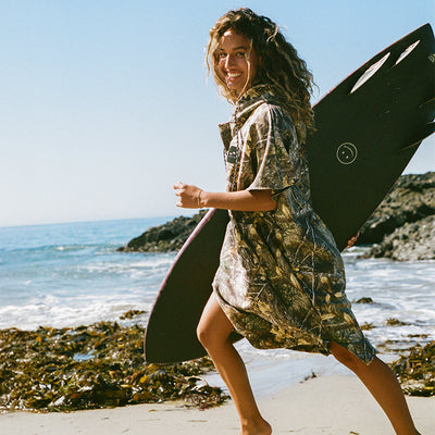 Quick-dry microfiber poncho with camouflage pattern on a rocky beach.
