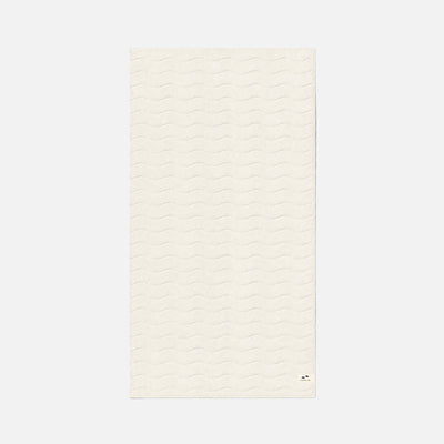 Cotton towel with subtle wavy texture, off-white, rectangular, plush fabric.
