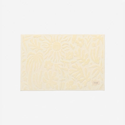 Bath mat, cream color with raised floral pattern, spa-inspired design.