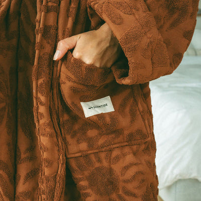 Plush terry cloth robe in brown with textured floral pattern and front pocket.