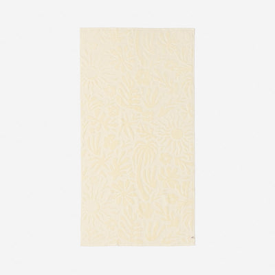 Cotton towel in beige with plush texture and subtle floral pattern for bathroom use.