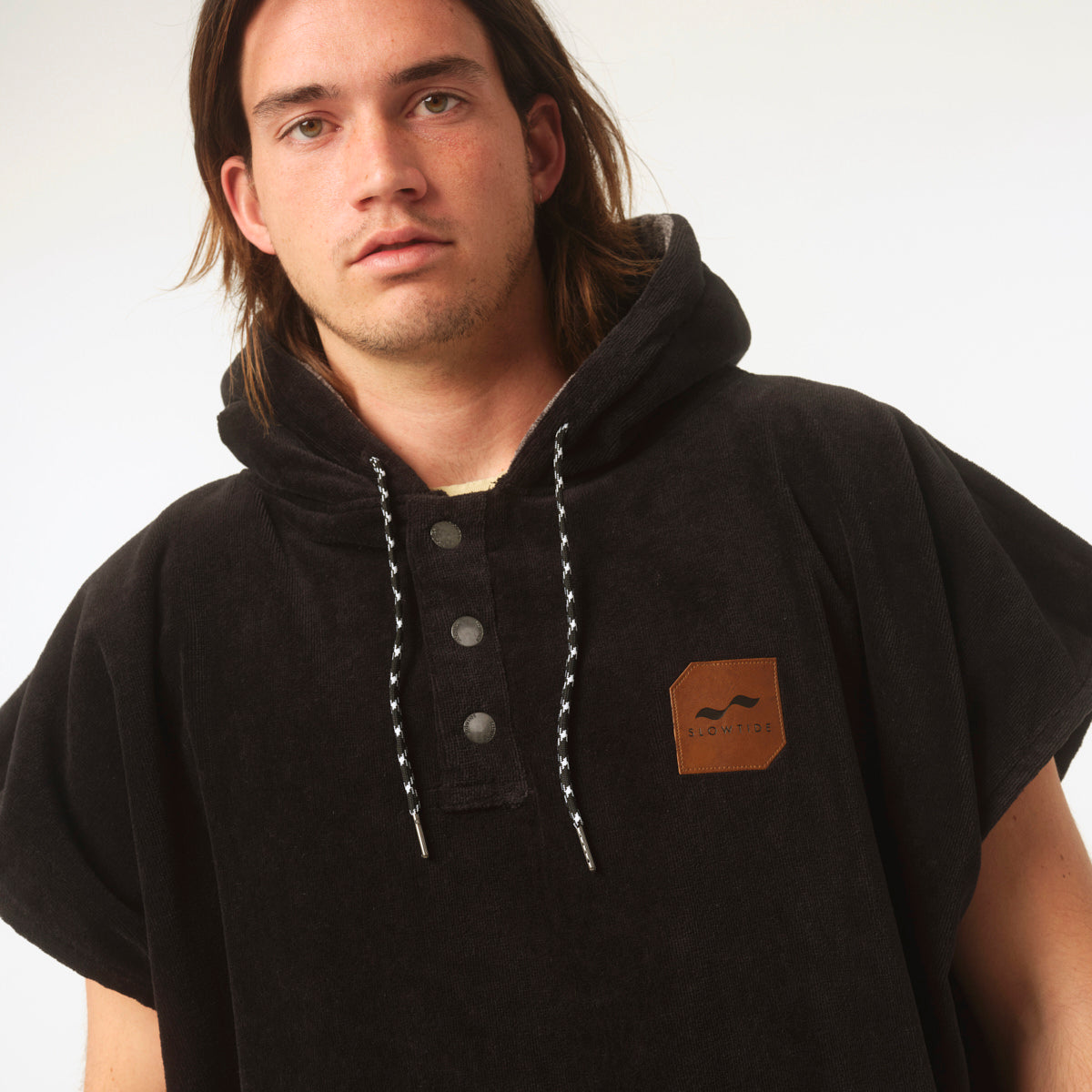 Black cotton terry hooded changing poncho with brown patch and white drawstrings.
