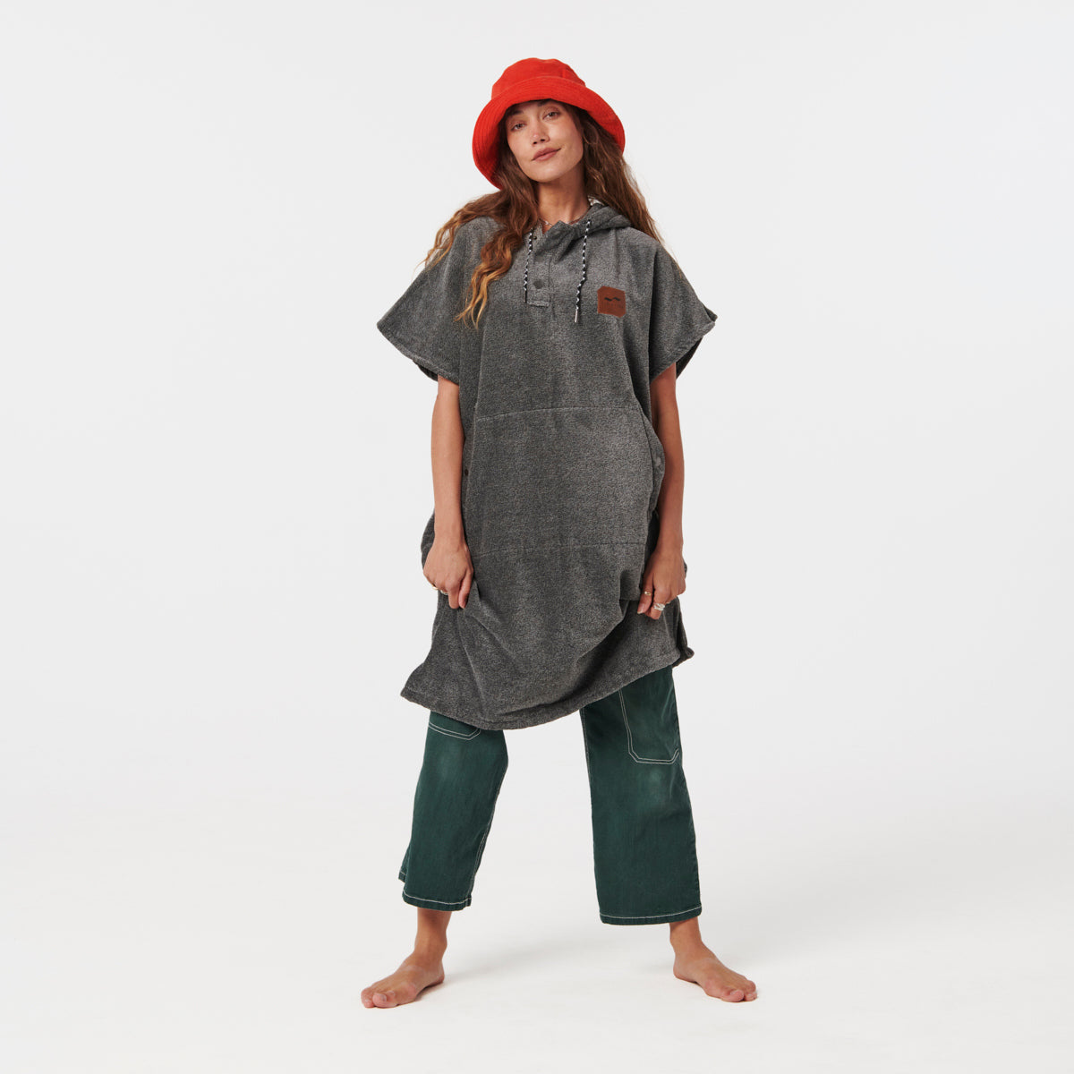 Gray towel poncho with hood, paired with green pants and red hat, displayed on white background.