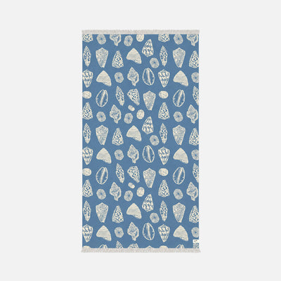 Blue sand-resistant towel with white seashell and coral pattern, fringed edges.