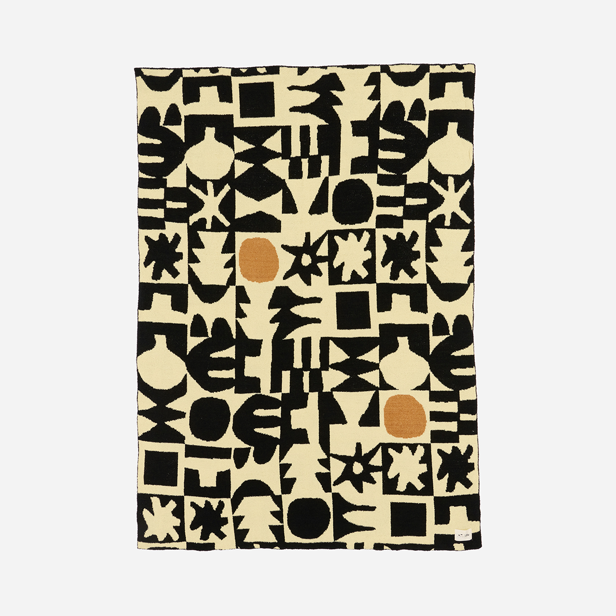 Plush knit throw with black geometric pattern and orange accents, modern style.