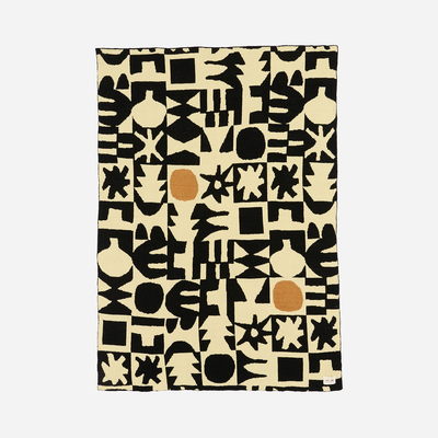 Plush knit throw with black geometric pattern and orange accents, modern style.
