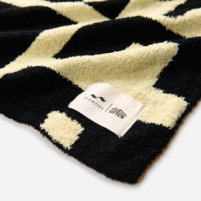 Blanket with black and cream modern art pattern, close-up on soft fabric texture.