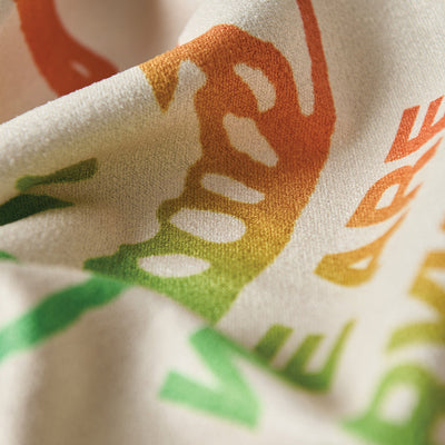 T-shirt fabric with green and orange text and abstract graphic pattern.