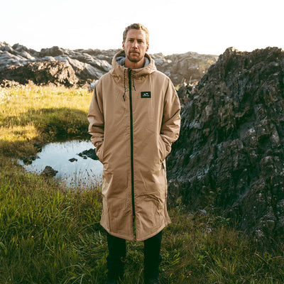 Tan all-weather parka with hood on grass outdoors.