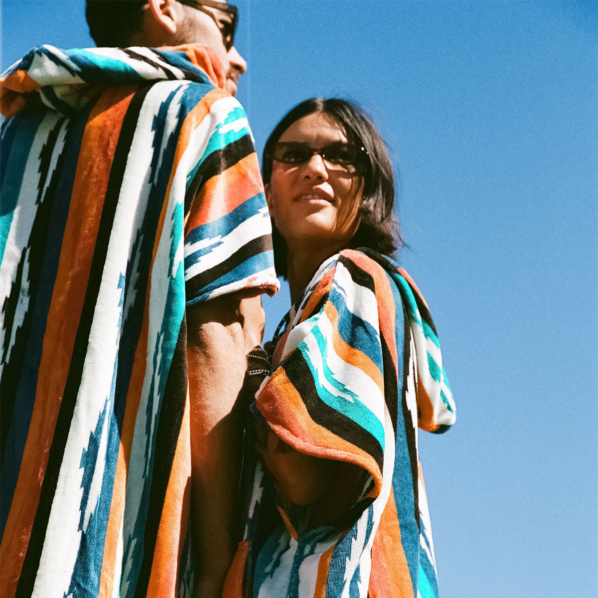 Cotton terry towel ponchos with colorful stripes and sunglasses.