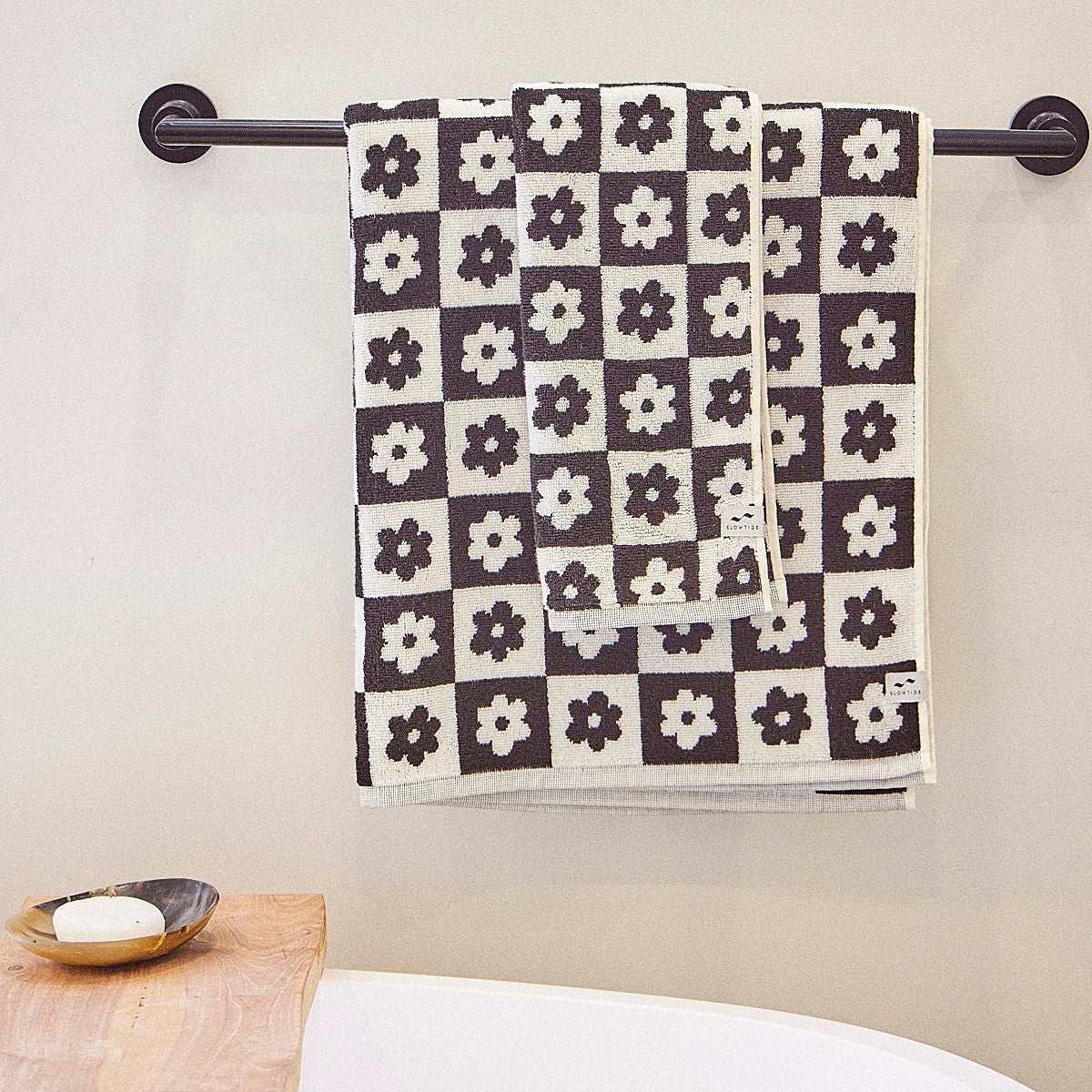 Hand towels, cotton, black and white pattern, hanging on a towel bar above bathtub.