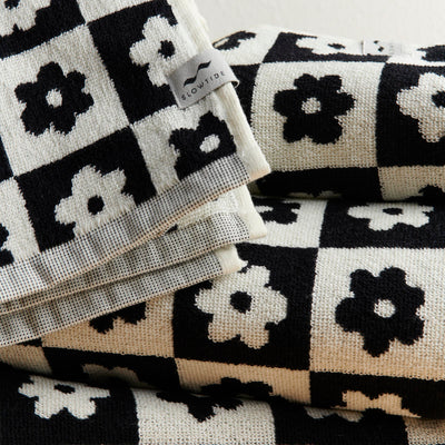 Hand towels with black and white checkerboard and floral patterns, neatly folded.