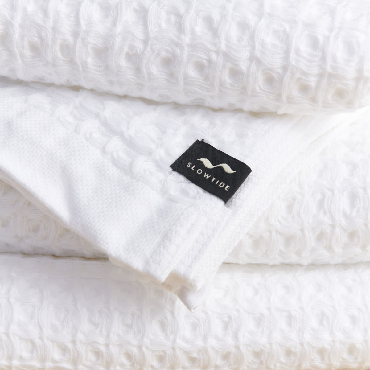 White waffle bath towels, absorbent, stacked neatly.