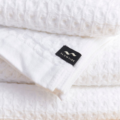 White waffle bath towels, absorbent, stacked neatly.