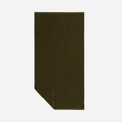 Quick dry olive green towel with waffle texture, neatly folded on plain background.
