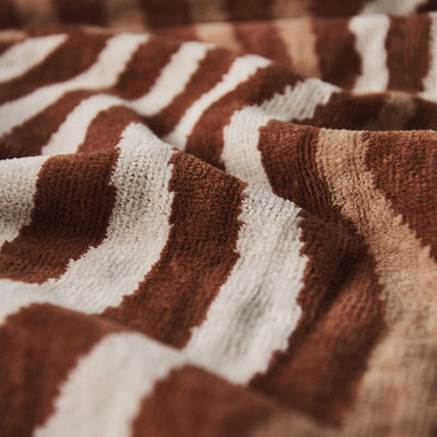 Textile fabric, textured, with retro wavy brown and cream stripe pattern, close-up view.