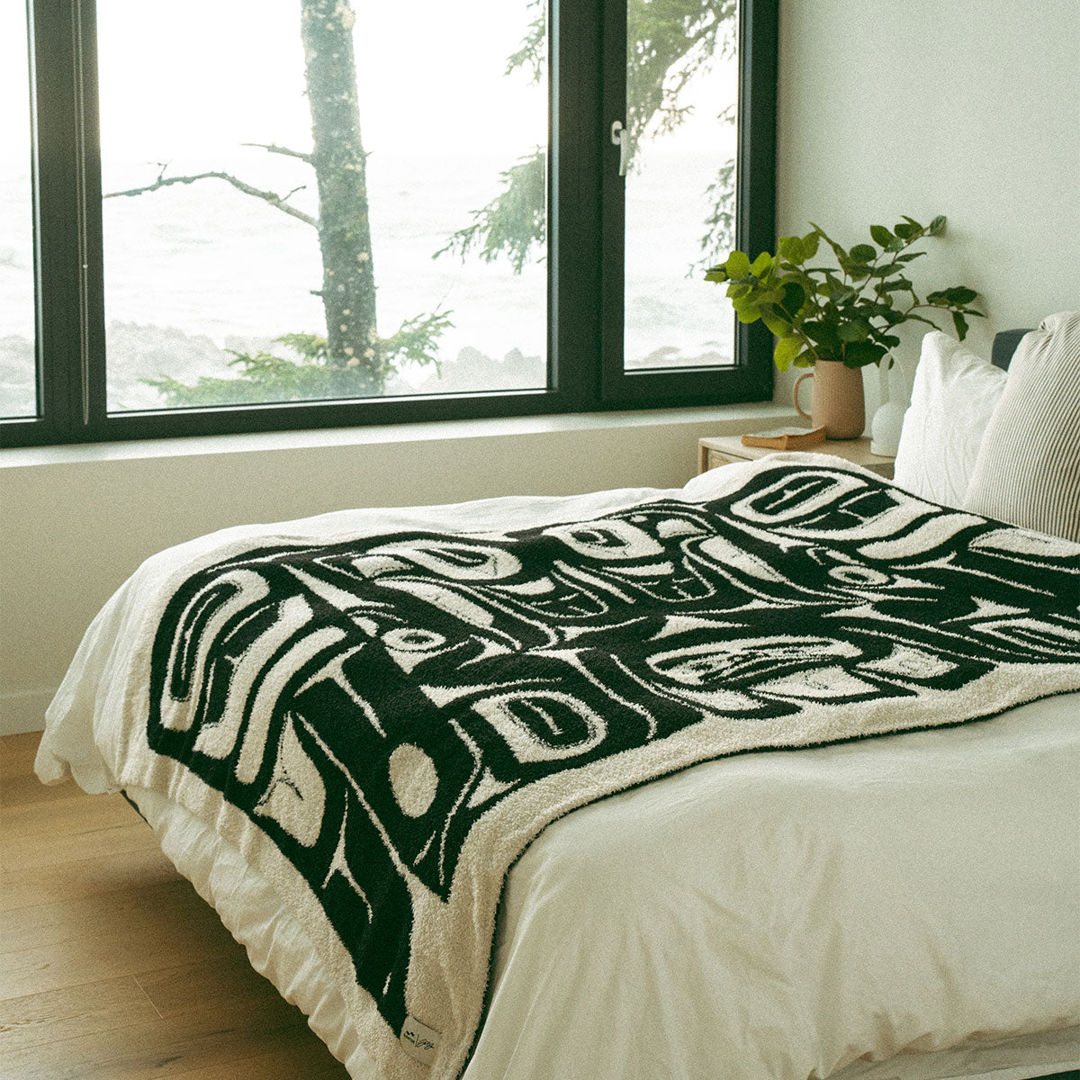 Bed with Tlingit-style blanket featuring eagle pattern in a well-lit room.