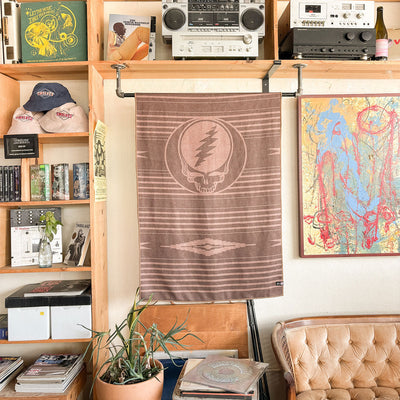 Brown recycled-material towel with graphic pattern displayed above a tan couch and shelves.