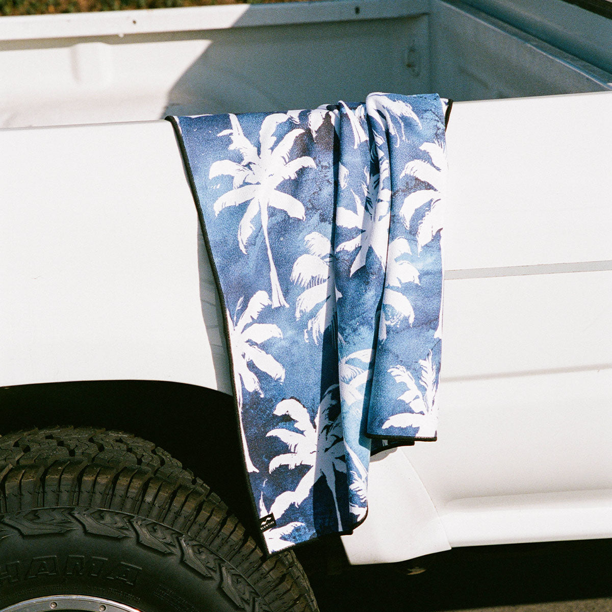 Blue tie-dye towel with soft fabric draped on a white truck bed.