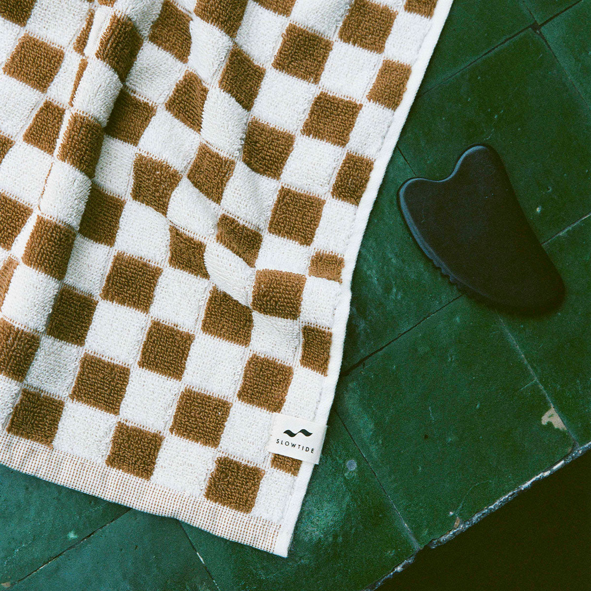 Hand towel, absorbent cotton, brown and white checkered pattern, shown with black gua sha tool.