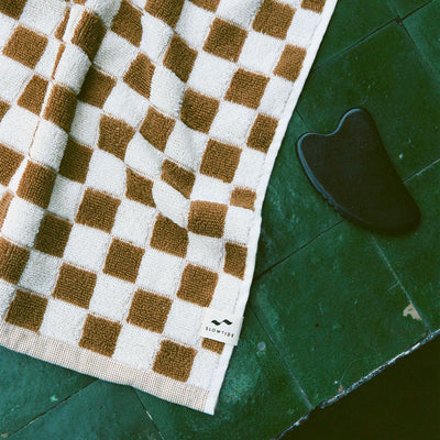 Hand towel, absorbent cotton, brown and white checkered pattern, shown with black gua sha tool.