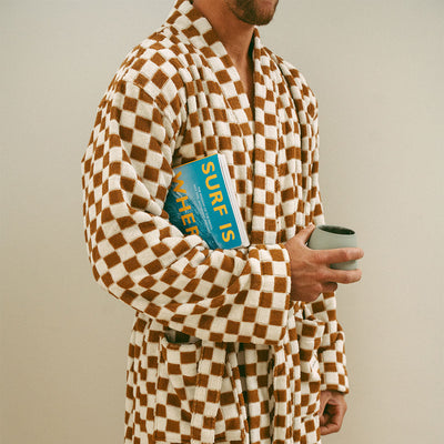 Terry cloth bathrobe in brown and white checkerboard with book and mug props.