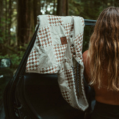 Quilted hooded surf poncho in tan and white geometric pattern draped over car door.
