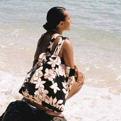 Floral beach bag with cotton canvas lining on a rock by the ocean.