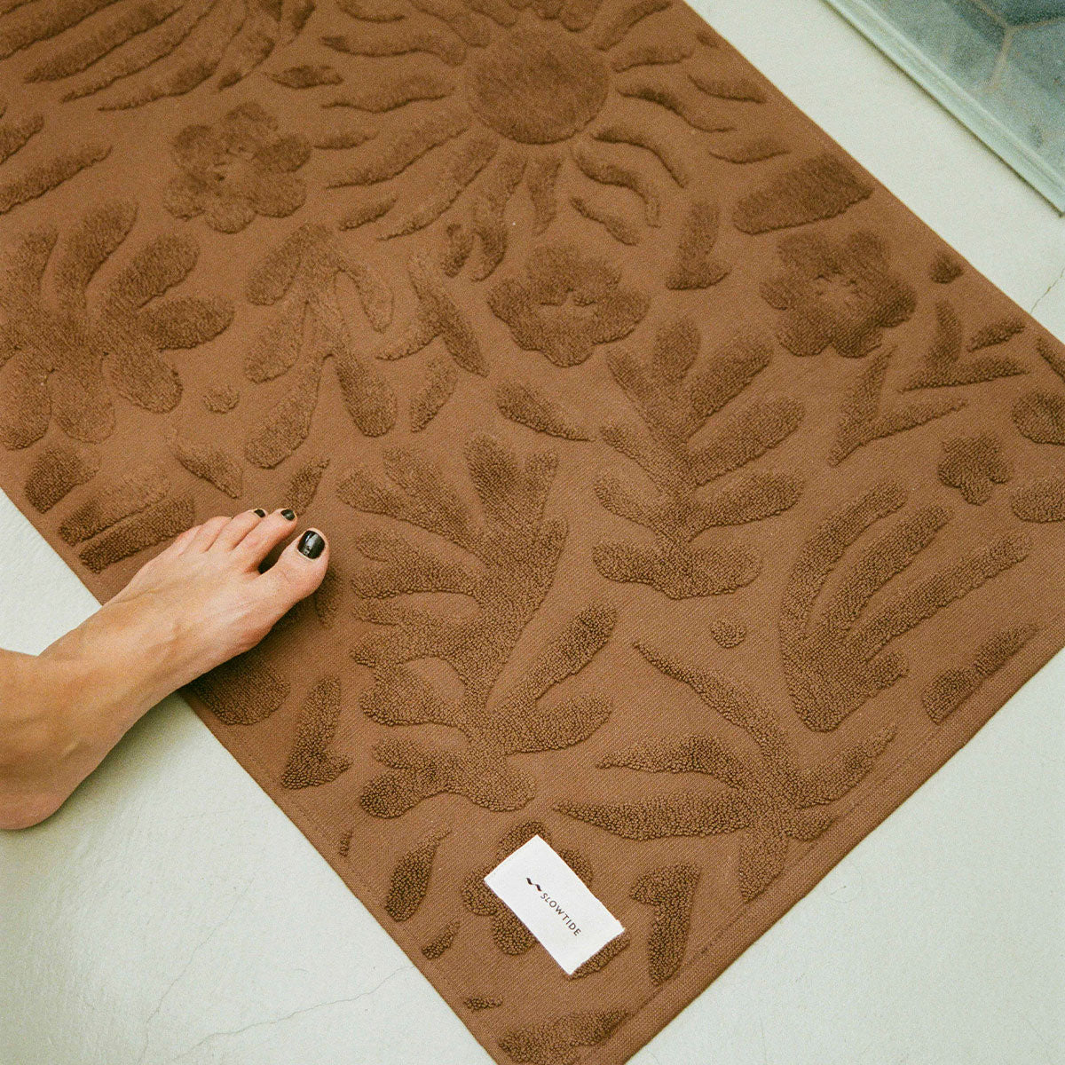 Cotton bath mat with a brown floral texture.