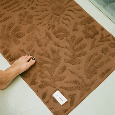 Cotton bath mat with a brown floral texture.