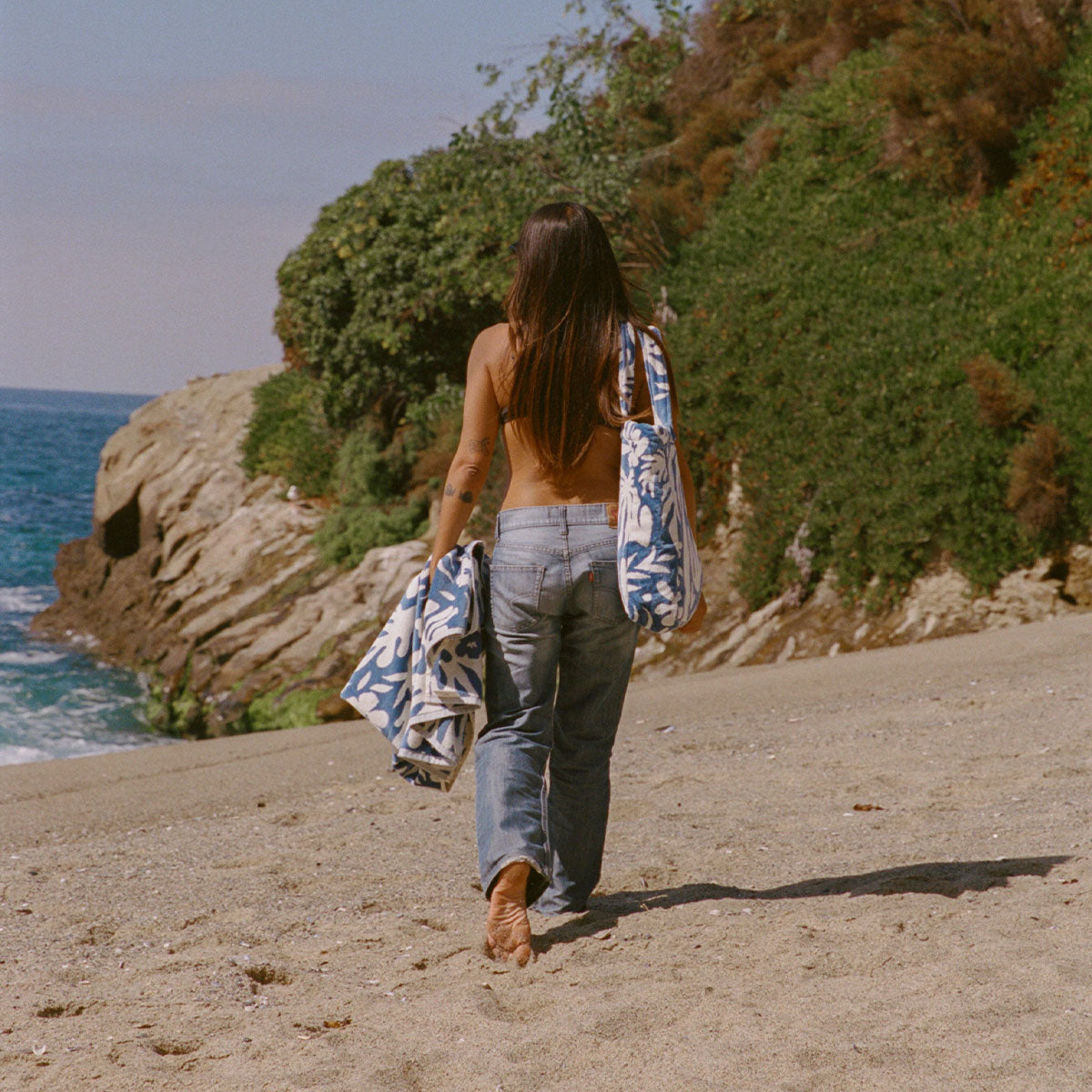 Beach totes with blue patterns, carried on sandy shore.
