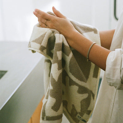 Hand towel with geometric pattern drying a plate in kitchen.