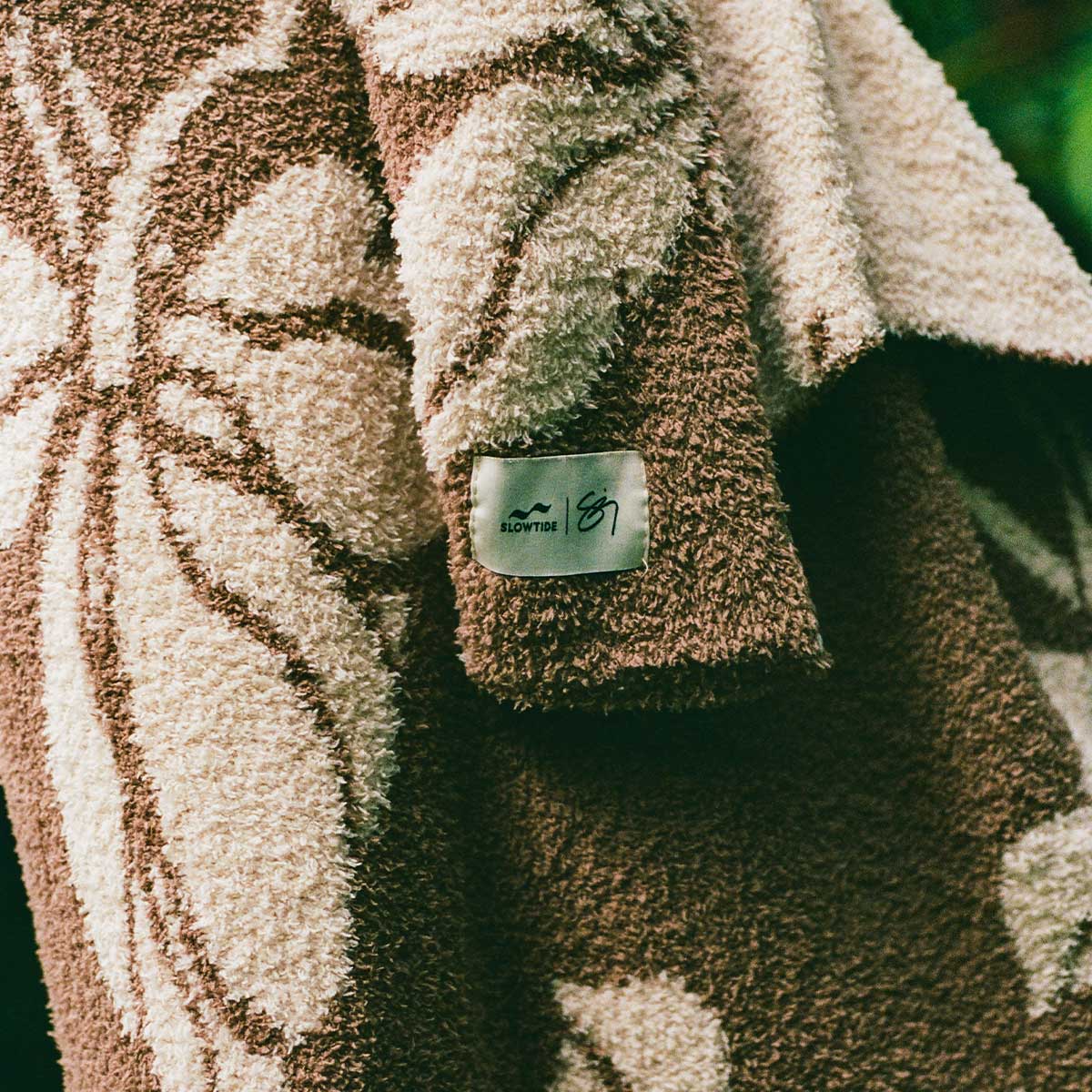 Plush knit fleece robe in a brown and cream floral pattern with a sleeve tag.